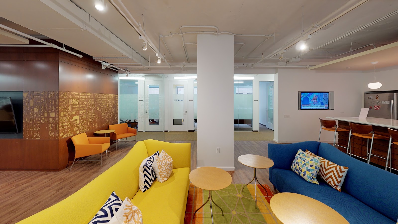 LocalWorks Connecticut Ave vibrant lounge with yellow and blue sofas, orange accent chairs, DC city map wall art, and colorful area rug