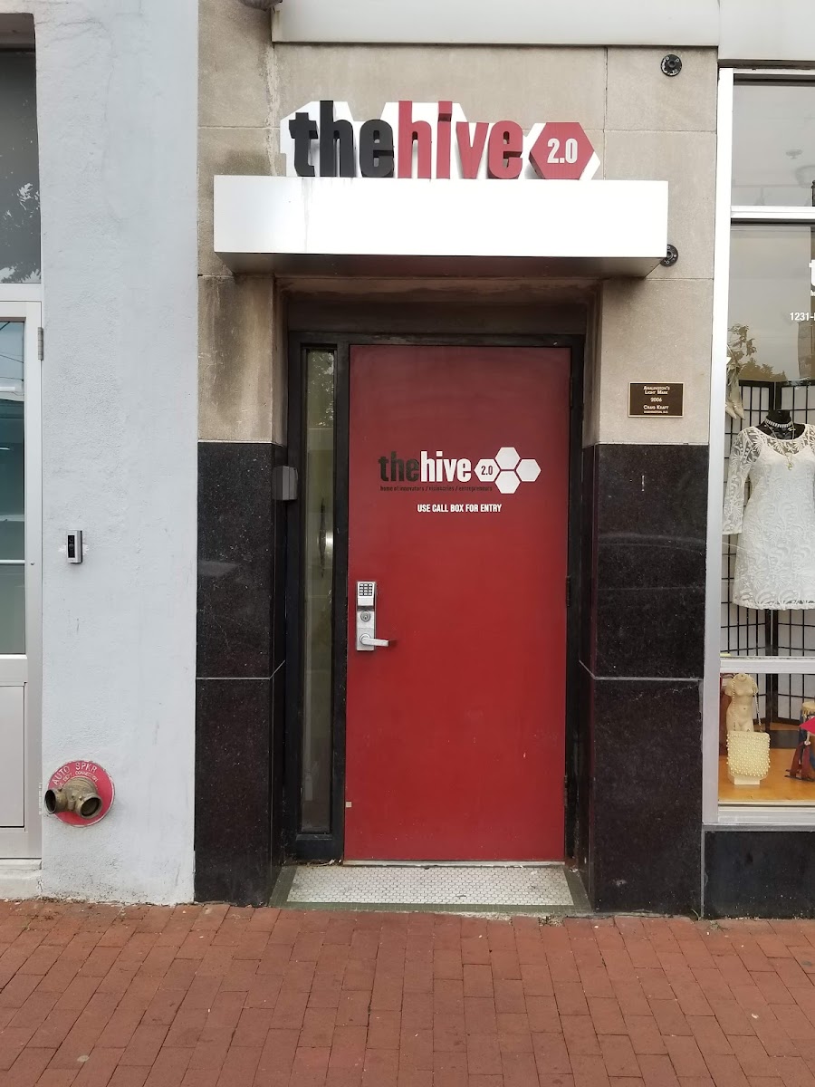 The Hive 2.0 street-level entrance with distinctive red door, thehive 2.0 branding sign, and call box entry on stone facade
