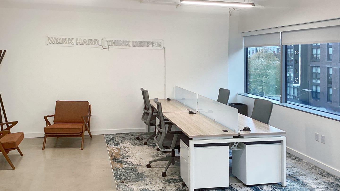 Spaces H Street minimalist private office with Work Hard Think Deeper wall art, shared desks with privacy screens, and mid-century accent chair