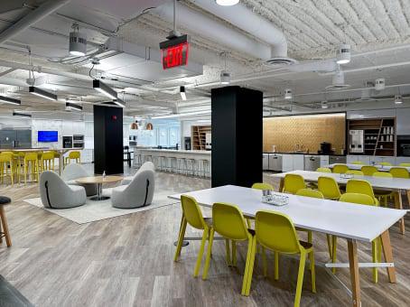 Spaces 1015 15th Street open area with lime green chairs, white communal table, gray bean bag lounges, and exposed ceiling with black columns