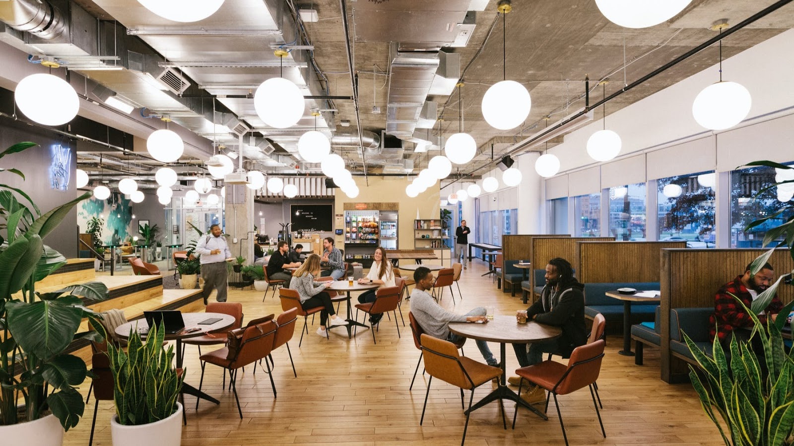 WeWork Capitol Riverfront open lounge with globe pendant lights, wood floors, plants and community seating